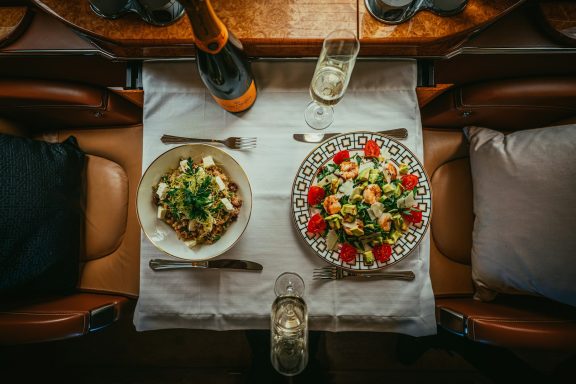 Mesa decorada con platos de pasta y ensalada, acompañados de champán.